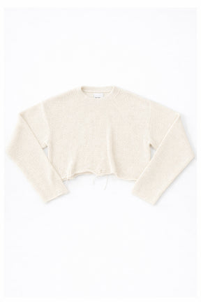 Cream cotton cropped knit sweater laid flat with soft texture and raw hem detail by Suss Knits