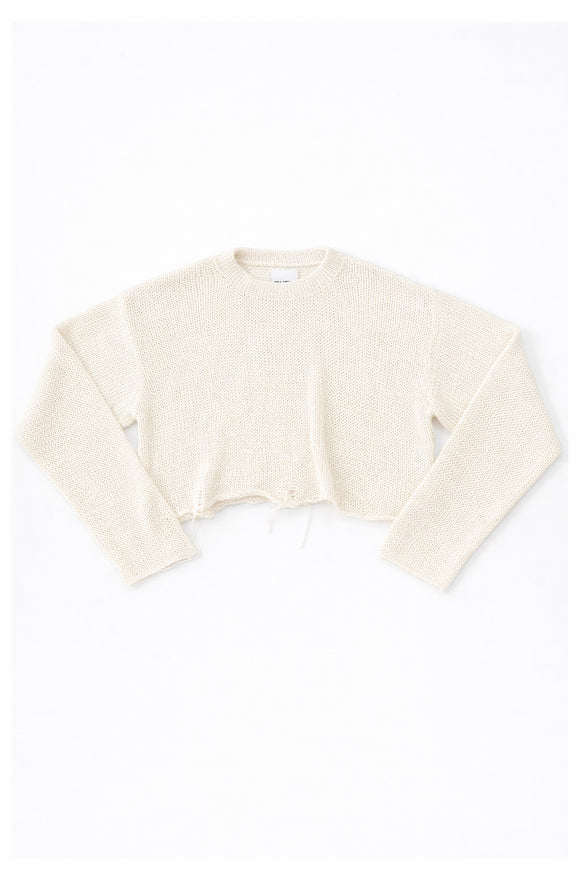 Cream cotton cropped knit sweater laid flat with soft texture and raw hem detail by Suss Knits