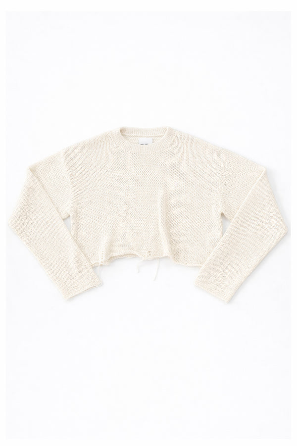 Cream cotton cropped knit sweater laid flat with soft texture and raw hem detail by Suss Knits