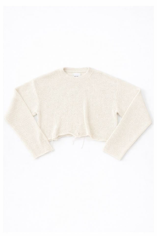 Cream cotton cropped knit sweater laid flat with soft texture and raw hem detail by Suss Knits