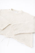 Angle detail of sleeves and distressed hem on cream cropped lightweight sweater