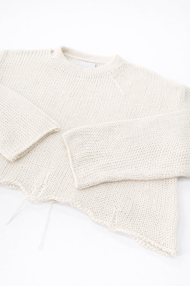 Angle detail of sleeves and distressed hem on cream cropped lightweight sweater