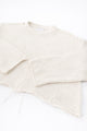 Angle detail of sleeves and distressed hem on cream cropped lightweight sweater