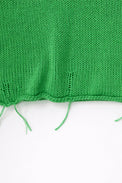 Close up detail of raw hem hand loomed green sweater with drop stitches
