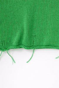 Close up detail of raw hem hand loomed green sweater with drop stitches
