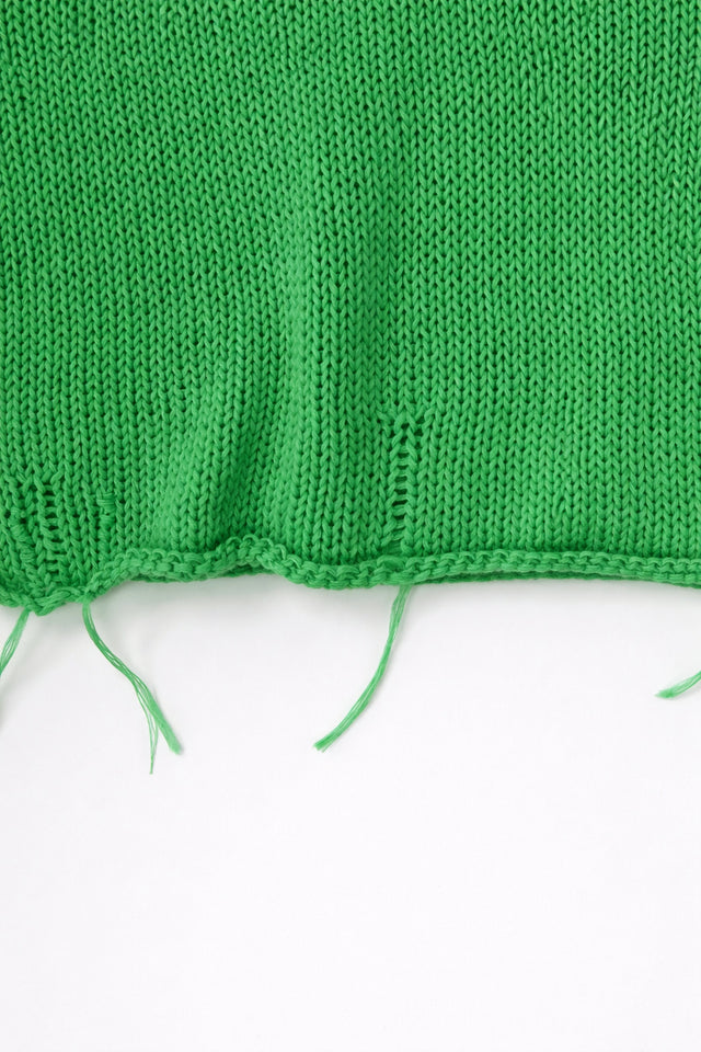 Close up detail of raw hem hand loomed green sweater with drop stitches