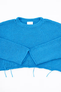 Cuff detail of turquoise hand loomed lightweight knit sweater with distressing details