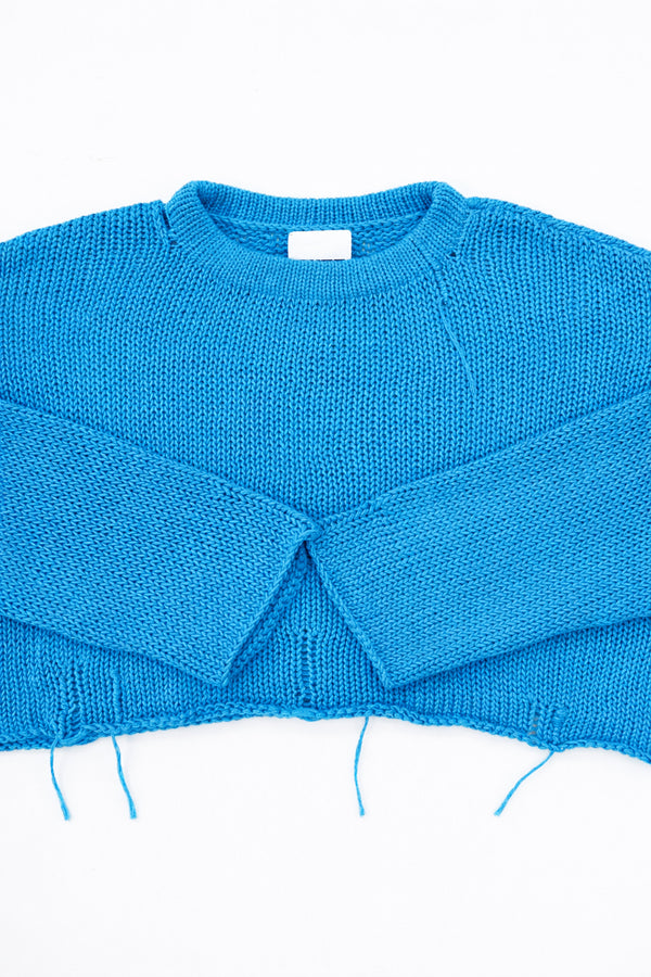 Cuff detail of turquoise hand loomed lightweight knit sweater with distressing details
