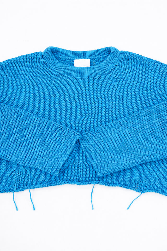 Cuff detail of turquoise hand loomed lightweight knit sweater with distressing details
