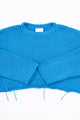 Cuff detail of turquoise hand loomed lightweight knit sweater with distressing details