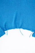 Raw hem detail of soft lightweight knit sweater hand loomed in turquoise recycled cotton yarn