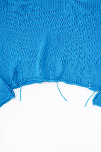 Raw hem detail of soft lightweight knit sweater hand loomed in turquoise recycled cotton yarn