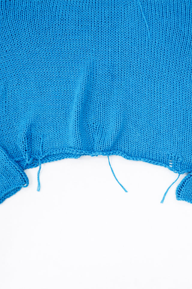 Raw hem detail of soft lightweight knit sweater hand loomed in turquoise recycled cotton yarn
