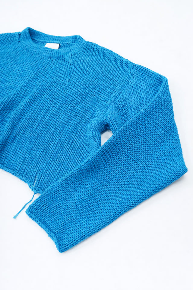 Angle detail shot of turquoise cotton knit light weight sweater with raw edges