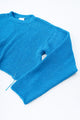Angle detail shot of turquoise cotton knit light weight sweater with raw edges