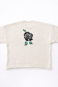 Back view of cream cotton rollneck sweater with a centered black rose