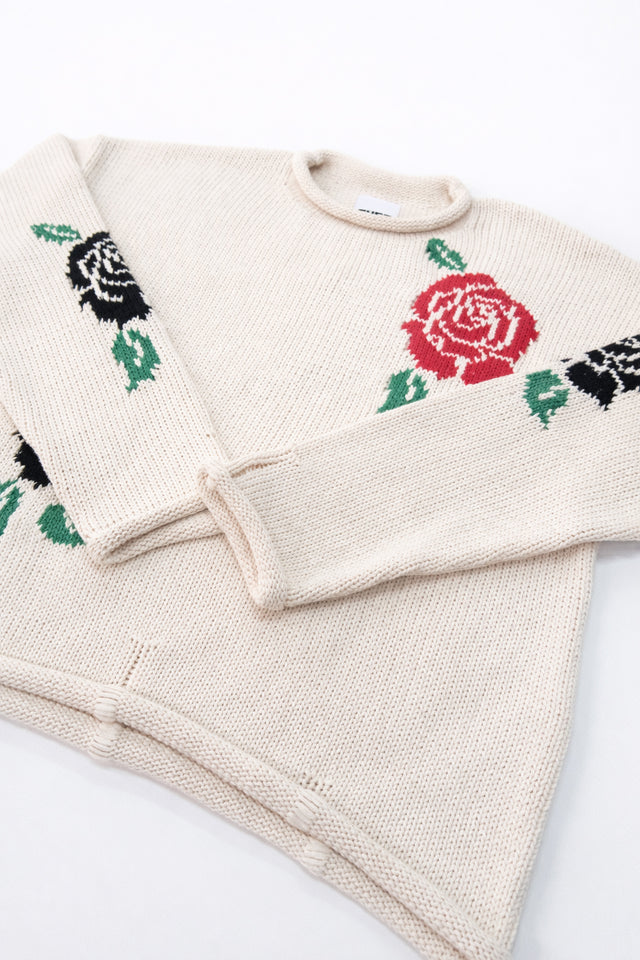 Angle view of our cream cotton hand loomed rollneck sweater with a red rose detail and texture detail of the cuffs