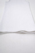 Flat lay detail of white knit tank hem showing textured ribbing and soft structure