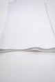 Flat lay detail of white knit tank hem showing textured ribbing and soft structure