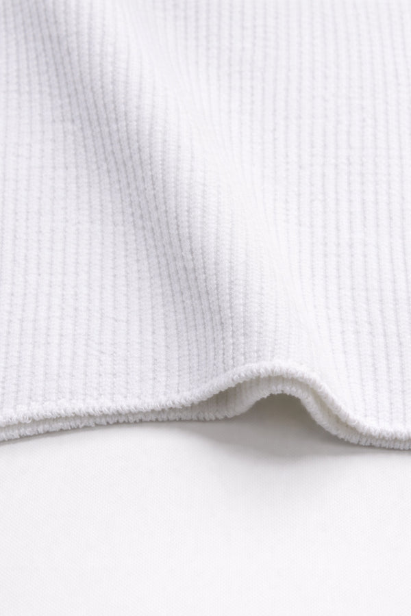 Close-up of ribbed texture and curved hem on white knit tank in recycled cotton blend