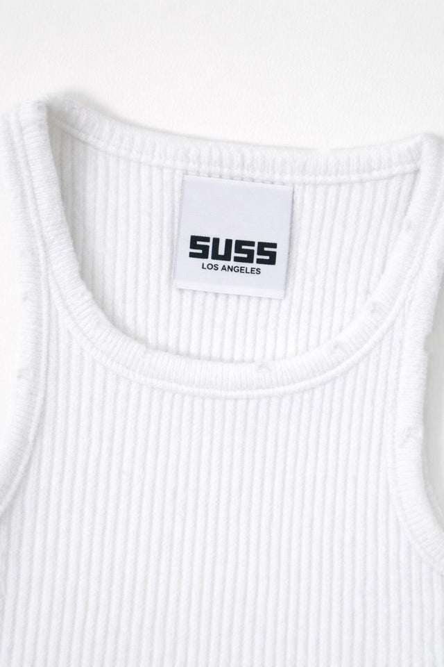 Close-up of white ribbed knit tank neckline with subtle tattered edge detail and Suss label