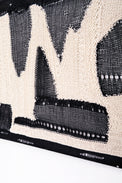 Layered textile detail showing hand knit, crocheted, and mesh elements in tonal black and cream abstract composition