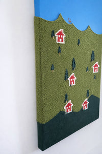 Detail of hand embroidered house on knitted wool landscape textile artwork and hand embroidered trees