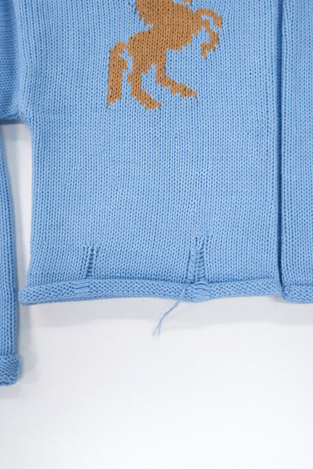 Hem detail of baby blue cotton cropped knit jacket with rolled edge finish