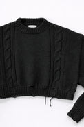 Close up of sleeve on black cropped knit sweater showing texture and distressed stitch details