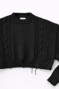 Close up of sleeve on black cropped knit sweater showing texture and distressed stitch details