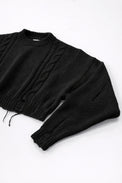 Close up of sleeve on black cropped knit sweater showing angle texture and distressed stitch detail