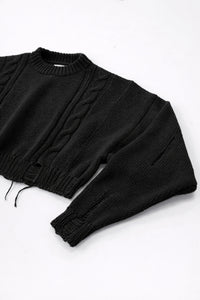 Close up of sleeve on black cropped knit sweater showing angle texture and distressed stitch detail