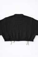 Back view of bright black cropped knit sweater with ribbed hem and subtle distressing