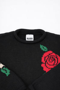 Collar and label detail of black cotton knit sweater with rose design by Suss Knits