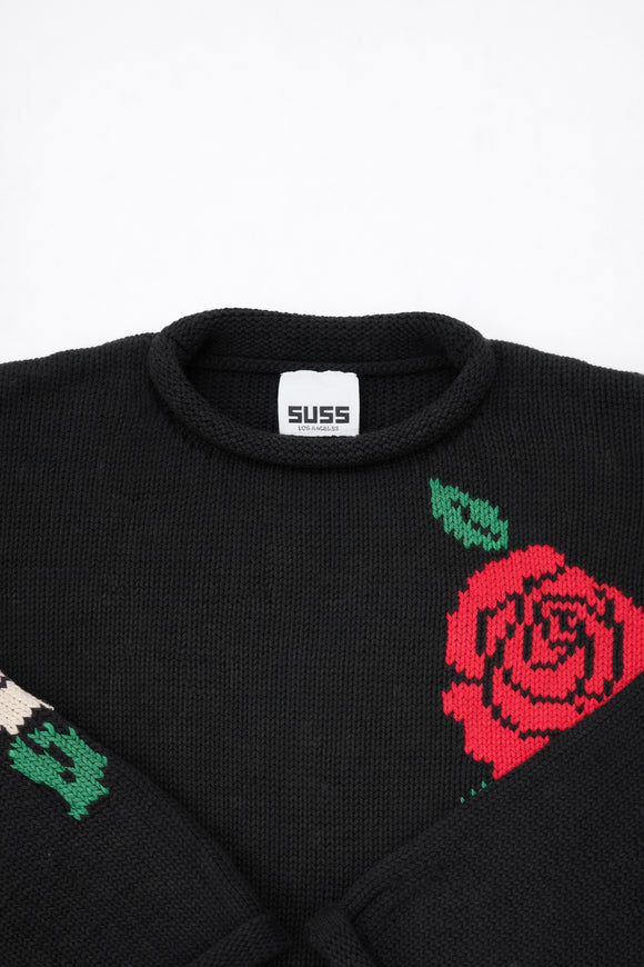 Collar and label detail of black cotton knit sweater with rose design by Suss Knits