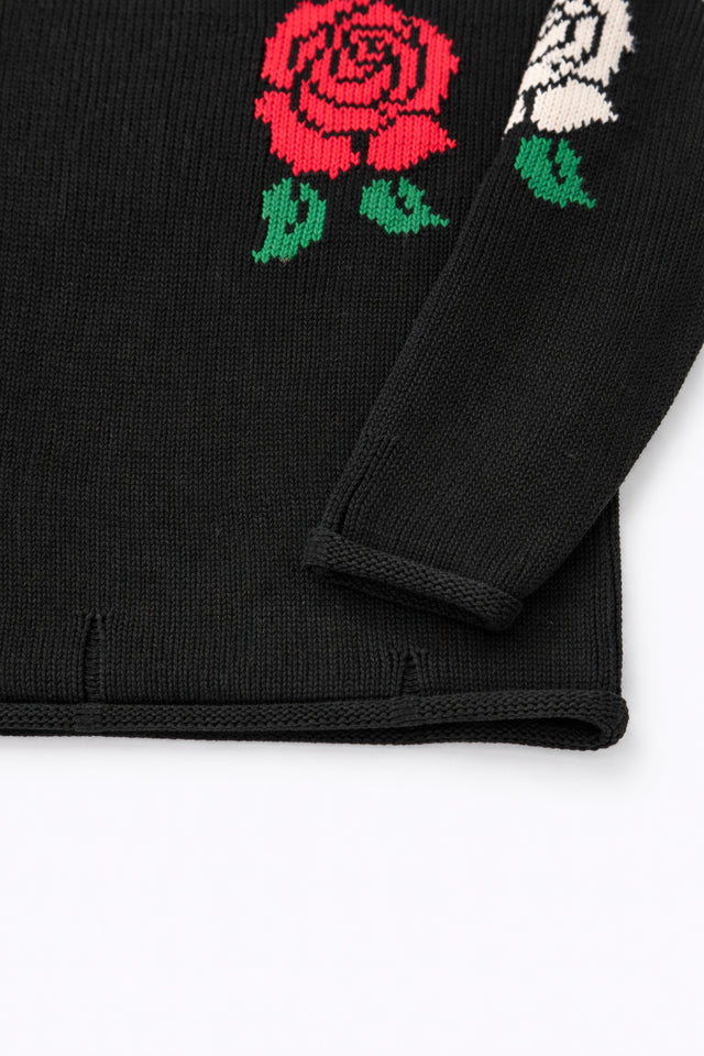 Sleeve and hem detail of black cotton knit sweater with rose intarsia by Suss Knits