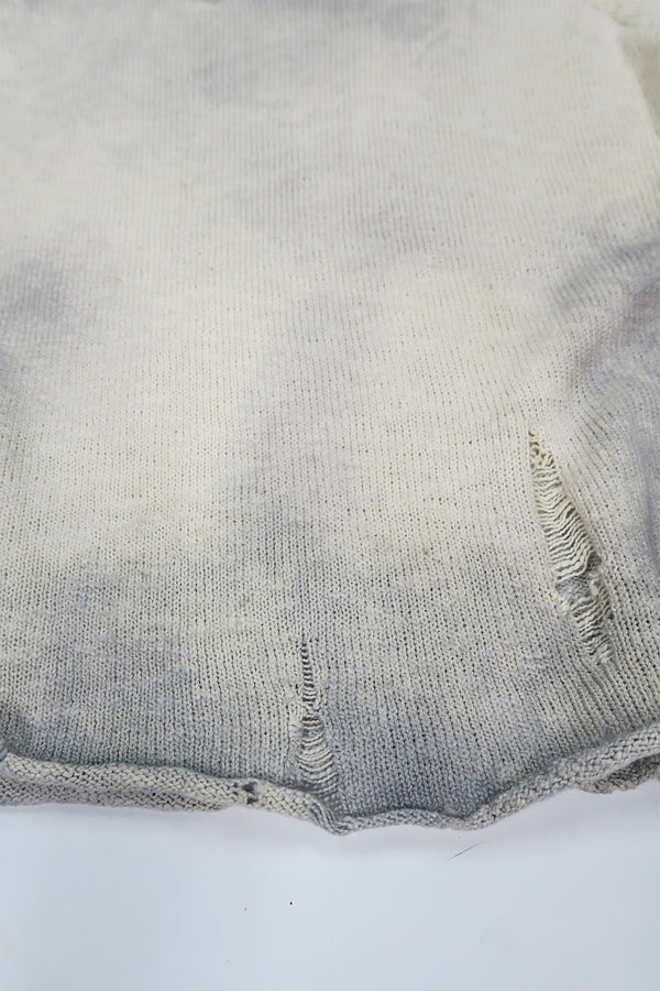 Close up detail of distressing and dye technique on the hem of the suss knits archive raglan sweater.