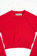 The Suss Knits Open Raglan knit in bright red cotton with raglan sleeves, laid flat on a white background. The brand label inside the collar reads 'SUSS KNITS'