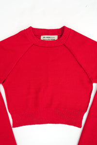 The Suss Knits Open Raglan knit in bright red cotton with raglan sleeves, laid flat on a white background. The brand label inside the collar reads 'SUSS KNITS'