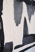 Side view of dimensional textile wall art showing depth of layered knit and mesh construction in black and cream