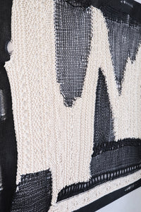 Side view of dimensional textile wall art showing depth of layered knit and mesh construction in black and cream