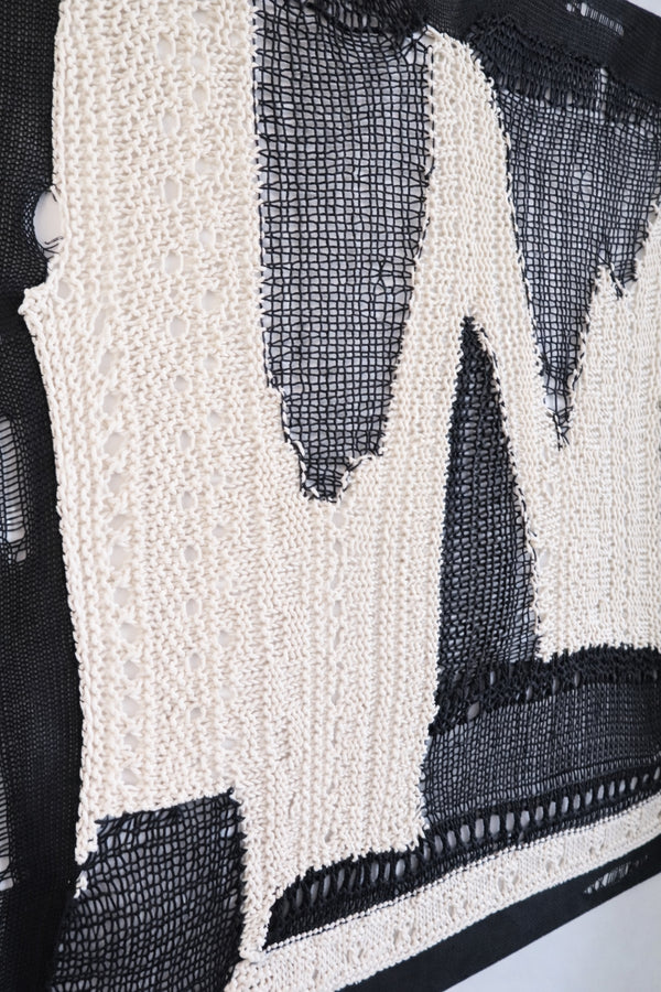 Side view of dimensional textile wall art showing depth of layered knit and mesh construction in black and cream