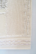 Close-up of right corner hand knit patchwork textile wall art showing mixed stitch patterns and textures in neutral cream tones