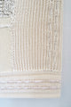 Close-up of right corner hand knit patchwork textile wall art showing mixed stitch patterns and textures in neutral cream tones