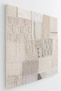 Side angle view of hand-stitched textile wall art detail showing embroidery and whip stitch construction on knit panels