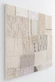 Side angle view of hand-stitched textile wall art detail showing embroidery and whip stitch construction on knit panels