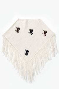 A cropped poncho knit in recycled cotton, cream base with brown and black horse motifs and long fringe