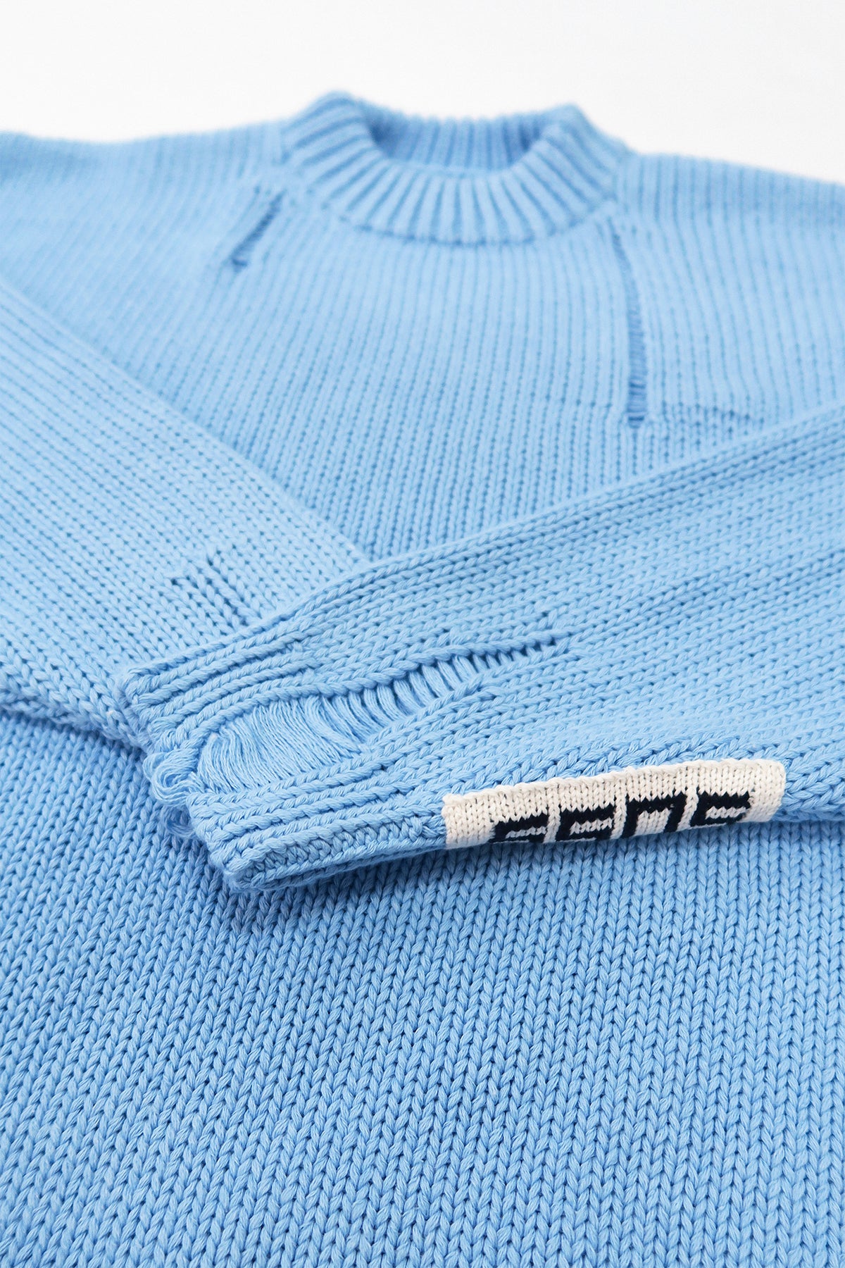 Close-up of ribbed cuff with handmade drop stitch detail on blue knit sweater