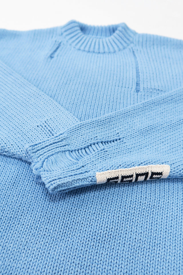 Close-up of ribbed cuff with handmade drop stitch detail on blue knit sweater