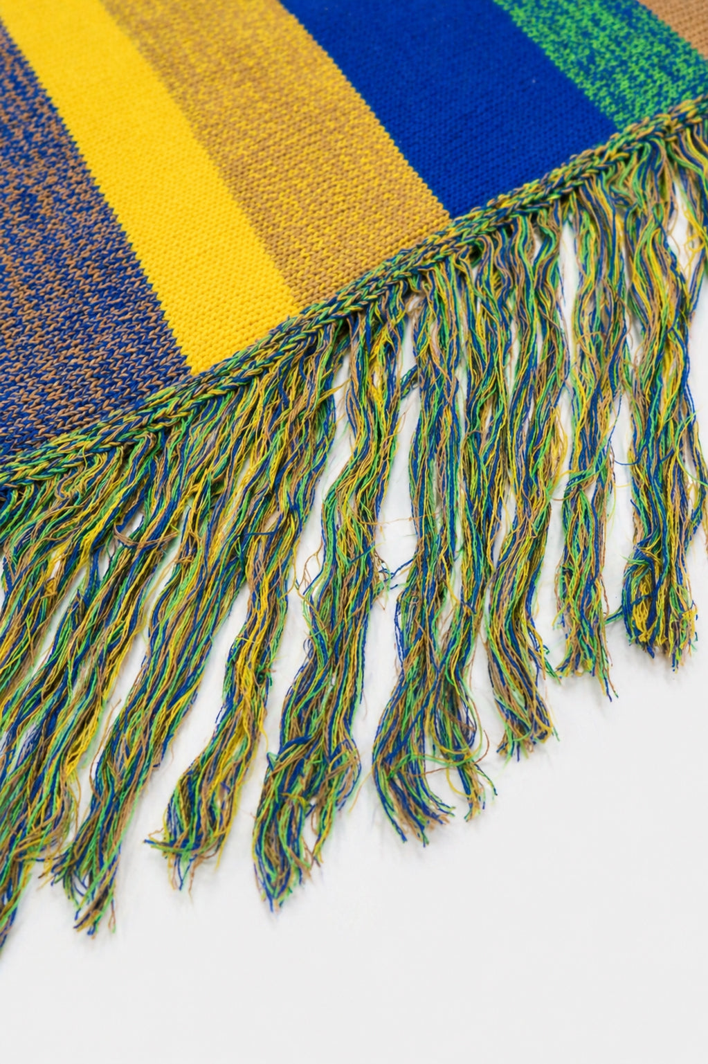 Close-up of layered multicolor fringe strands on striped recycled cotton poncho